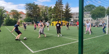 Powiększ grafikę: Uczniowie wraz z nauczycielami grają w piłę nożną na boisku szkolnym. W tym momencie piłkę przechwycił uczeń.