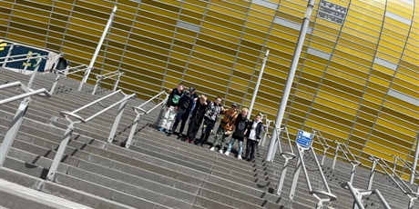 Powiększ grafikę:  chłopców sypiących na schodach. W tle żółta kopuła stadionu Polsat Arena