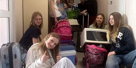 Powiększ grafikę: 6 uczennic stoi na korytarzu szkolnym, 4   dziewczynki siedzą na podłodze.