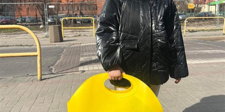 Powiększ grafikę: Dziewczynka stojąca na dworze, trzyma w ręku koszyk żółty koszyk ze sklepu Biedronka