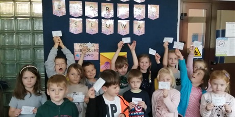 Powiększ grafikę: Uczniowie trzymają karteczki z sentencjami, a za nimi jest napis "dobre słowa"