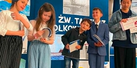 Powiększ grafikę:  3 dziewczynki i 3 chłopców stoją z książkami w ręku na tle niebieskiej tablicy z kampusem Prowadź nas kapitanie