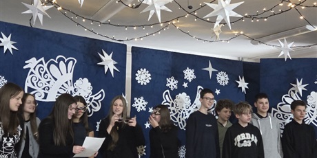 Powiększ grafikę: Uczniowie klasy 8 zgromadzeni na scenie śpiewają kolędę w języku angielskim