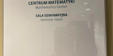 Powiększ grafikę: Na żółtej ścianie, przywieszona biała kartka z napisem CENTRUM MATEMATYKI Mathematics Center SALA SEMINARYINA Seminarroom