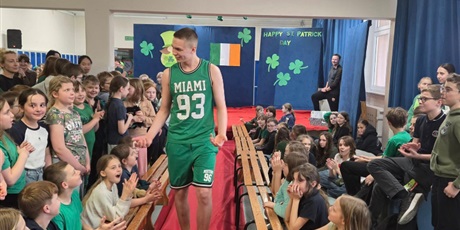 Powiększ grafikę: Uczeń ubrany na zielono idzie po czerwonym dywanie