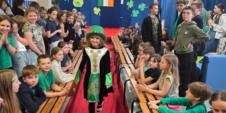 Powiększ grafikę: Dziewczynka w zielonym kapeluszu idzie po czerwonym dywanie