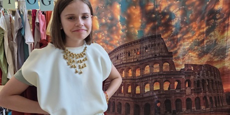 Powiększ grafikę: Dziewczynka stoi na tle obrazu Koloseum ubrana w strój rzymski