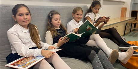 Powiększ grafikę: Cztery dziewczynki z klasy 4 b siedzą na kanapie i czytają książkę.