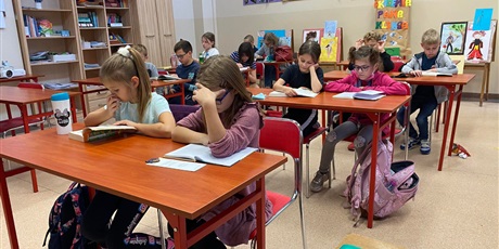 Powiększ grafikę: Uczniowie z klasy 4a siedzą w ławkach i czytają książki.