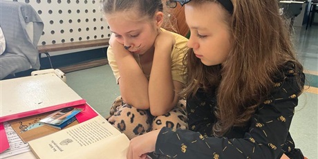 Powiększ grafikę: Dwie dziewczynki czytają książkę. Jedna z nich jest tygryskiem. 