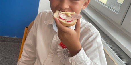 Powiększ grafikę: Uśmiechnięty chłopiec jedzący kanapkę