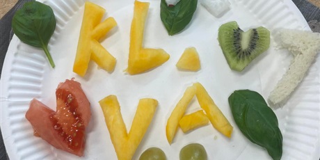 Powiększ grafikę: Na talerzu z owoców utworzony napis kl. V A, serduszko z pomidora i kiwi, uśmiech z winogron i papryczki