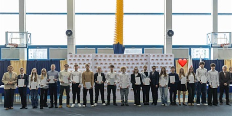 Powiększ grafikę: Grupa uczniów stojących w rzędzie z dyplomami w ręku w tle tablica z herbem Gdańska