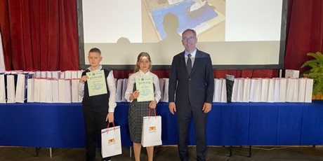 Powiększ grafikę: Klara Niedbała prezentuje swój dyplom, obok niej stoi chłopiec. Towarzyszy im dyrektor szkoły. 