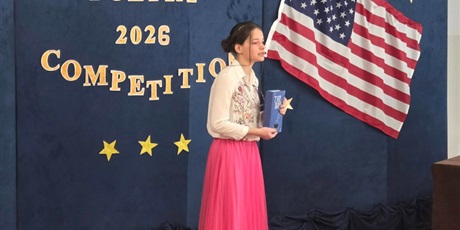 Powiększ grafikę: Dziewczynka w białej bluzeczce i różowej spódniczce z książką w dłoni recytuje wiersz