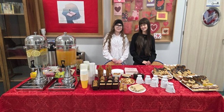 Powiększ grafikę: Dwie dziewczynki stoją za stołem z napojami i przekąskami