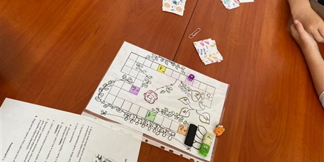 Powiększ grafikę: Na zdjęciu widać planszę gry „Zagadki tajemniczego ogrodu”, pionki, kostkę, karty do gry.