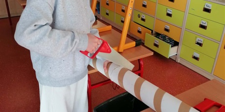 Powiększ grafikę: Dziewczynka piłuje konstrukcję do projektu